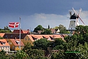 w oddali symbol miasteczka , potężny Gudhjem Molle, nad czerwonymi dachami rozpościera skrzydła holenderski wiatrak